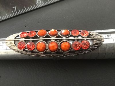 Sale Photo Thumbnail #79: Elongated statement ring featuring a textured silvertone openwork setting encrusted with faceted orange rhinestones and opaque orange cabochon/bead accents. Features an adjustable band on the back. The top measures approximately 2.5 inches in length. In g