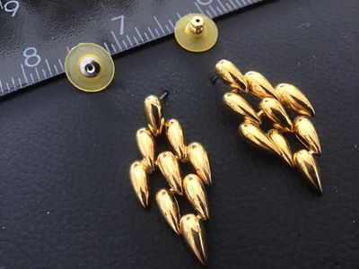 Sale Photo Thumbnail #73: Pair of vintage gold-tone fashion pierced earrings featuring articulated, multi-tiered teardrop shaped links. Includes bullet clutch plastic disc earring backs. Show light wear consistent with age and use. Measures approximately 1.5 inches long.