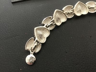 Sale Photo Thumbnail #65: Silver-tone costume jewelry link bracelet featuring heart-shaped scrollwork links set with vibrant multi-colored heart crystals (red, purple, blue, green). Measures approximately 7.5 to 8 inches in length. In good condition with light surface wear.