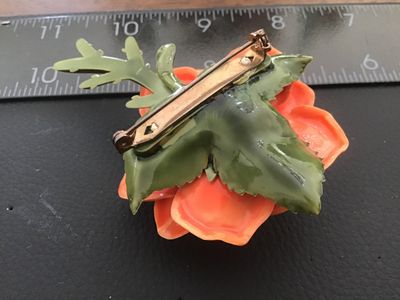 Sale Photo Thumbnail #33: Vintage dimensional orange rose brooch crafted from molded celluloid/plastic material with green stem and leaves on the back. Features a safety pin style clasp mechanism attached to the back. Measures approximately 2.5 inches across. Good pre-owned vintag