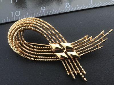 Sale Photo Thumbnail #12: Vintage Monet gold-tone brooch featuring textured, twisted rope strands in a modern abstract loop design with polished diamond-shaped central accents. Signed 'MONET ©' on the back. Measures approximately 2.75 inches long. Features a standard rollover saf