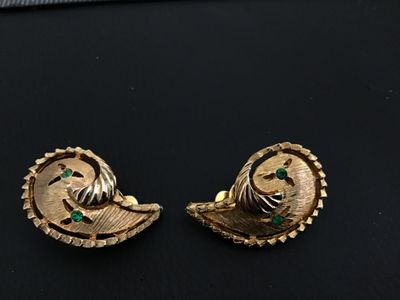 Sale Photo Thumbnail #143: Pair of vintage gold-tone textured paisley swirl clip-on earrings featuring small green rhinestone accents. Each earring measures approximately 1 inch long. In good vintage condition with minor surface wear consistent with age.