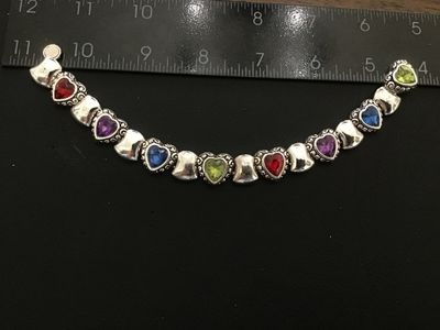 Sale Photo Thumbnail #63: Silver-tone costume jewelry link bracelet featuring heart-shaped scrollwork links set with vibrant multi-colored heart crystals (red, purple, blue, green). Measures approximately 7.5 to 8 inches in length. In good condition with light surface wear.