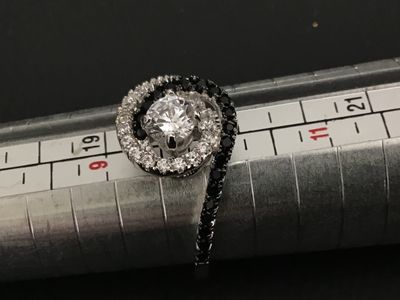 Sale Photo Thumbnail #186: silver bypass swirl ring featuring a central clear round cubic zirconia or crystal, surrounded by swirling bands of pave-set clear and black stones. Marked 925 on the inner band. Measures approximately size 9.5 on a ring mandrel. Good condition with light