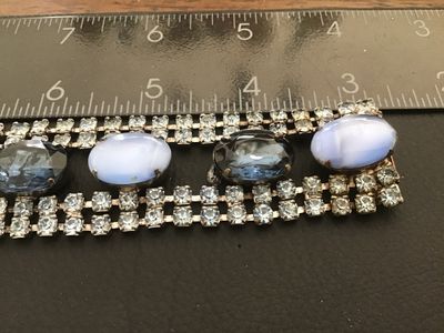 Sale Photo Thumbnail #39: Vintage wide costume jewelry bracelet featuring alternating faceted dark blue rhinestones and light blue opaque oval cabochons set between double rows of clear rhinestones. Silver-tone metal setting with a fold-over clasp. Measures approximately 7 inches 