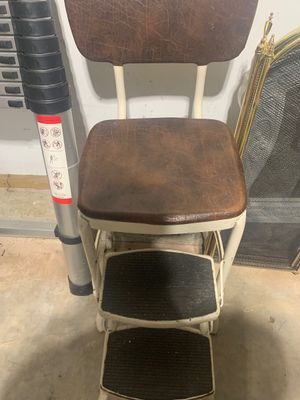 Sale Photo Thumbnail #17: Vintage Cosco-style step stool chair with cream metal frame, pull-out steps, and distressed brown vinyl upholstery on the seat and backrest.