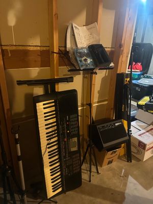 Sale Photo Thumbnail #19: Yamaha electronic keyboard resting vertically on a stand alongside a Singtrix karaoke system setup, music stand, speaker, and microphone stand.