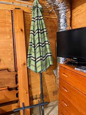 Sale Photo Thumbnail #9: Green and brown striped outdoor patio umbrella standing next to a Samsung flat-screen television and a wooden dresser.