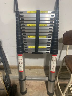 Sale Photo Thumbnail #14: Telescoping aluminum extension ladder with black plastic fittings, rubber feet, and a securing hook-and-loop strap.