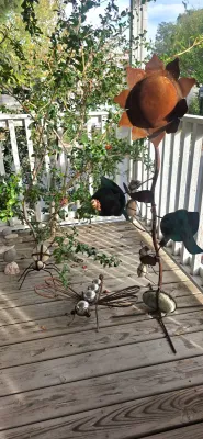 Sale Photo Thumbnail #36: Collection of rustic metal outdoor yard art including a tall sunflower stake, a dragonfly sculpture, and spider figures incorporating river rocks.
