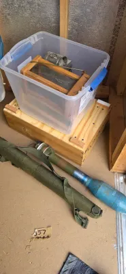 Sale Photo Thumbnail #31: Inert military training ordnance with carrying case alongside a clear plastic storage bin filled with vintage glass lantern parts and wooden components.