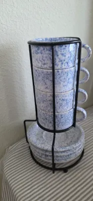 Sale Photo Thumbnail #89: Set of four blue and white splatter-glazed ceramic cups and saucers in a black wire metal stacking caddy rack.