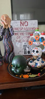 Sale Photo Thumbnail #104: Collection of Halloween and macabre decor, including a figure inspired by Edvard Munch's 'The Scream', a Mexican Day of the Dead tree of life, a green crackle doll head, and a humorous novelty sign.