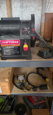 Sale Photo Thumbnail #28: Craftsman benchtop belt and disc sander displayed on a metal shelf alongside various workshop accessories and tools.