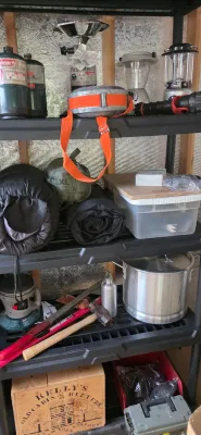 Sale Photo Thumbnail #27: Black plastic shelving unit stocked with camping gear, including propane cylinders, a vintage canteen, lanterns, sleeping bags, and a large stock pot.