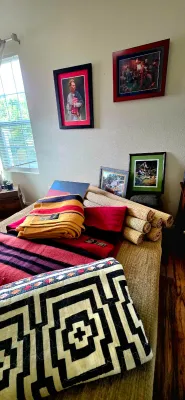 Sale Photo Thumbnail #49: Assortment of Southwestern-style textiles, Hudson's Bay-style striped wool blankets, rolled grass mats, and framed artwork displayed on a bed.