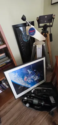 Sale Photo Thumbnail #100: Vixen Porta alt-azimuth telescope mount on tripod, paired with framed space artwork and a telescope tube assembly in a soft case.