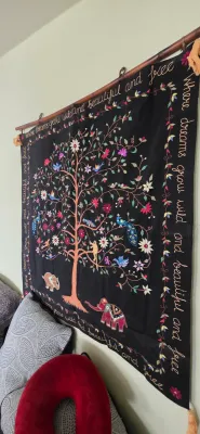 Sale Photo Thumbnail #94: Black embroidered fabric wall hanging featuring a central tree of life motif with birds, elephants, and cursive lettering around the border.