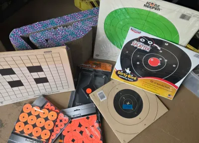 Sale Photo Thumbnail #29: Assortment of target shooting supplies, including Birchwood Casey splatter targets, Champion spinner target, and various paper bullseye targets.