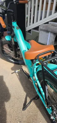 Sale Photo Thumbnail #40: Modern turquoise electric bicycle featuring a step-through frame, tan leatherette saddle and handlebar grips, integrated rear rack, and fat tires.