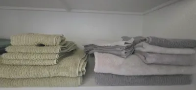 Sale Photo Thumbnail #41: Stacks of folded bath towels, hand towels, and washcloths in neutral shades of beige and gray arranged on a closet shelf.
