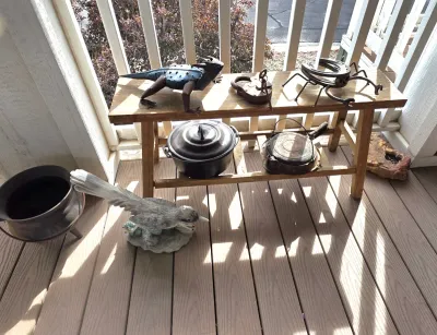 Sale Photo Thumbnail #39: Rustic metal sculptures including a metal lizard and a horseshoe spider, displayed alongside cast iron cookware and a wooden bench.