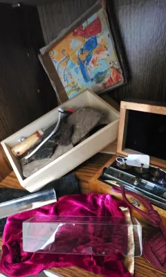 Sale Photo Thumbnail #17: Collection of mixed vintage items including a small wooden box of brass scale weights, clear optical prisms, a small framed painting, and velvet storage bags.