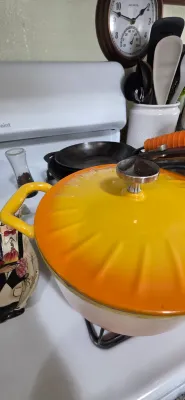 Sale Photo Thumbnail #77: Vibrant yellow and orange gradient enameled cast iron Dutch oven with lid, resting on a stove top.