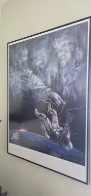 Sale Photo Thumbnail #103: Framed surrealist art print depicting an astronaut floating in space beneath ethereal religious figures, housed in a thin black frame.