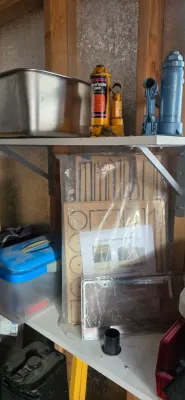 Sale Photo Thumbnail #30: Workshop shelving storing a stainless steel basin, bottle jacks, a plastic storage tub, and a packaged wooden model kit.