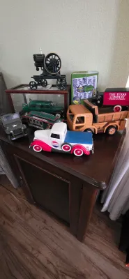 Sale Photo Thumbnail #96: Collection of vintage-style toy vehicles, including a Pepsi-Cola pickup truck, a wooden dump truck, a military jeep, and a cast iron hit-and-miss engine model on a wooden cabinet.