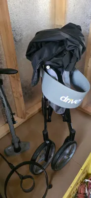 Sale Photo Thumbnail #26: Drive Medical folding rollator walker with a grey padded backrest and black storage bag, alongside a bicycle tire pump.