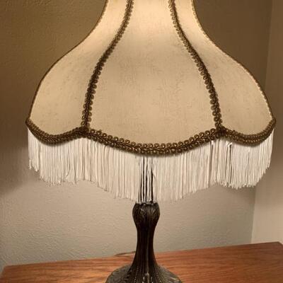 Replica of a Vintage Lamp. Appears to have aluminum base and cloth fringe lampshade. It works and is 21 inches tall.