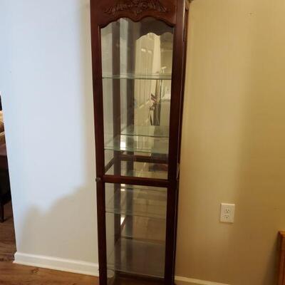 Slim lighted curio cabinet in a cherry finish. Cabinet has 4 glass shelves. Could not get light to work, may just need a new bulb....