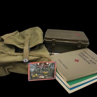 This lot contains military memorabilia like books, first aid kit, USAF bag, and a Desert Storm trading card....