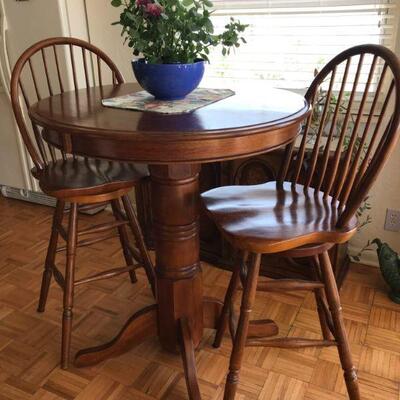 Solid wood bar table with two swivel chairs. 36â€ diameter and 42â€ tall.
