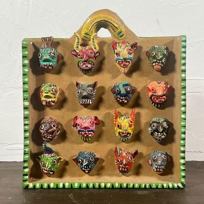 MEXICAN MASK CERAMIC  |  Ceramic wall hanging displaying miniature colorful masks, signed "Ortega" on the side - w. 8 3/4 x h....