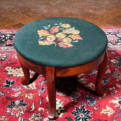 NEEDLEPOINT FOOTSTOOL  |  20th century, a cluster of flowers on a green ground, over cabriole legs - h. 12 x dia. 15 in.

