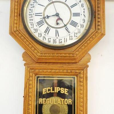 1022	ANTIQUE ECLIPSE CALENDAR REGULATOR WALL CLOCK IN PRESSED OAK CASE, APPROXIMATELY 17 IN WIDE X 33 IN HIGH
