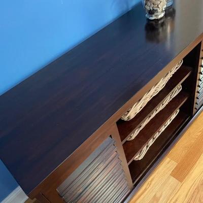 This classic style console features two doors for storage and a 3-shelf display.  Baskets included.