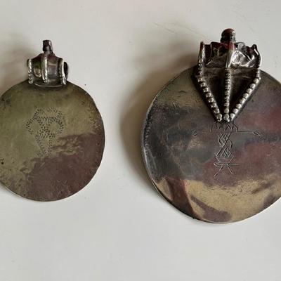 A pair of Omani silver Samt pendants with text from the Quran on the front and a shackled jinn on the reverseâ€”these were worn to ward...
