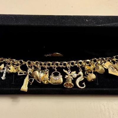 14K Gold Bracelet with charms including a locket, a cross, an ice skate, a frog, the Empire State Building, a heart, a handbag...