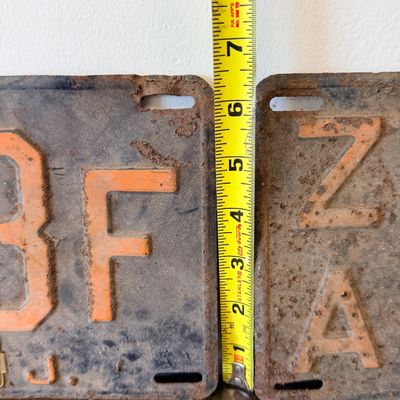 Sale Photo Thumbnail #56: Matching pair of vintage 1956 New Jersey metal license plates, registration number ZA 23F. Each plate features embossed orange characters on a dark background with an attached metal '56' tab (stamped 1665727). Both plates show significant age, surface rus
