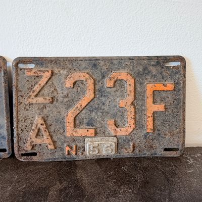 Sale Photo Thumbnail #46: Matching pair of vintage 1956 New Jersey metal license plates, registration number ZA 23F. Each plate features embossed orange characters on a dark background with an attached metal '56' tab (stamped 1665727). Both plates show significant age, surface rus