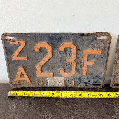 Sale Photo Thumbnail #55: Matching pair of vintage 1956 New Jersey metal license plates, registration number ZA 23F. Each plate features embossed orange characters on a dark background with an attached metal '56' tab (stamped 1665727). Both plates show significant age, surface rus