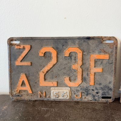 Sale Photo Thumbnail #40: Matching pair of vintage 1956 New Jersey metal license plates, registration number ZA 23F. Each plate features embossed orange characters on a dark background with an attached metal '56' tab (stamped 1665727). Both plates show significant age, surface rus