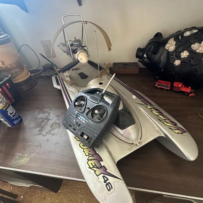 Vintage gas-powered Vortex 46 remote control hydroplane boat with transmitter controller, featuring an air-propeller engine design.
