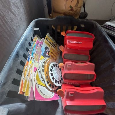 Collection of vintage red GAF View-Master viewers and assorted picture reels stored in a plastic crate.