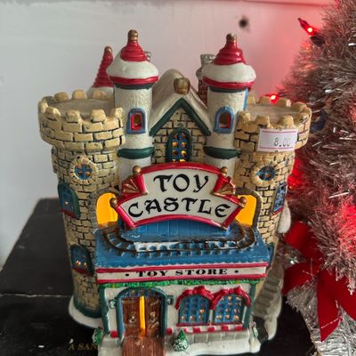 Hand-painted miniature ceramic Christmas village building titled "Toy Castle", featuring interior lighting and detailed castle...