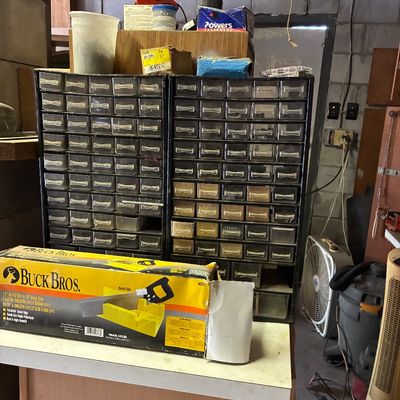 A boxed Buck Bros. 12-inch miter box and 14-inch back saw sitting in front of two vintage multi-drawer hardware storage cabinets filled...